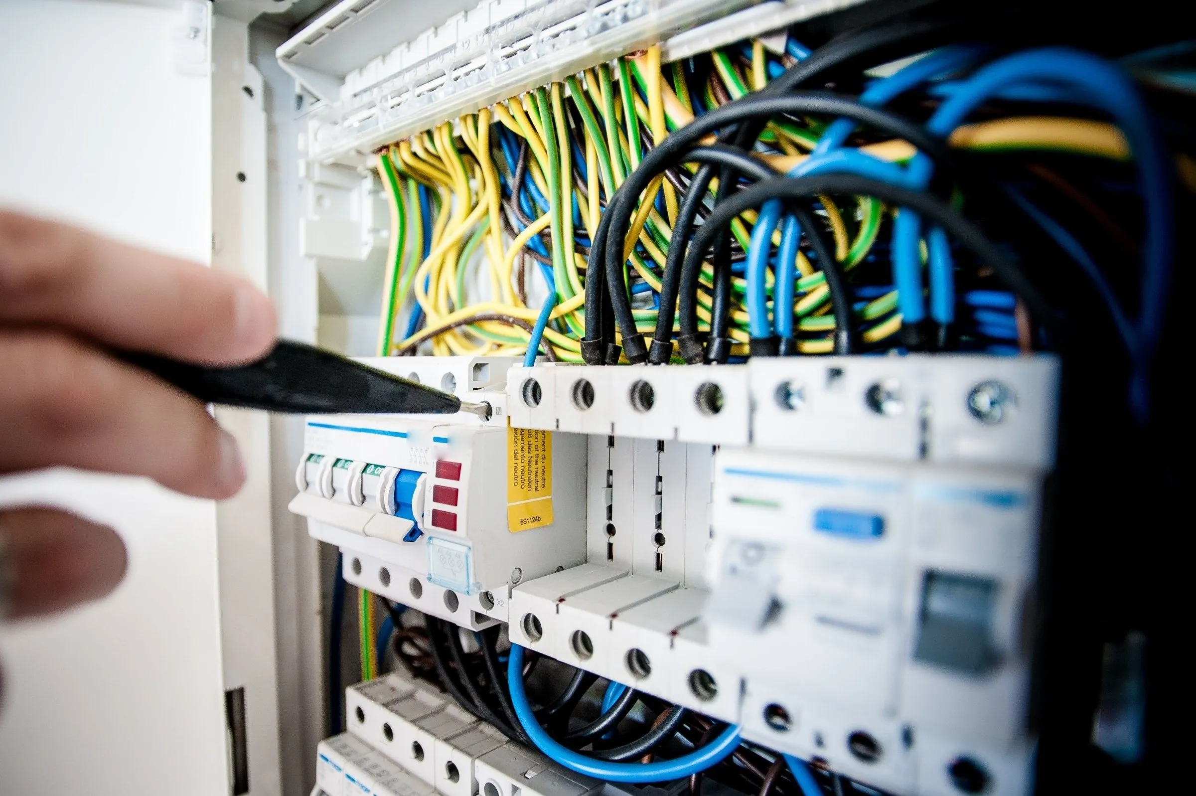 An electrician testing a terminal in an open consumer unit