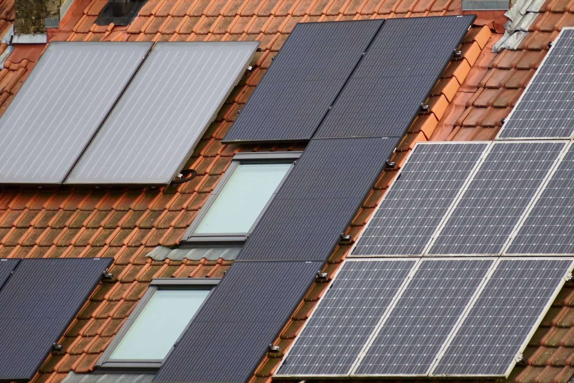 Solar panels on a row of terraced roofs with roof windows between them